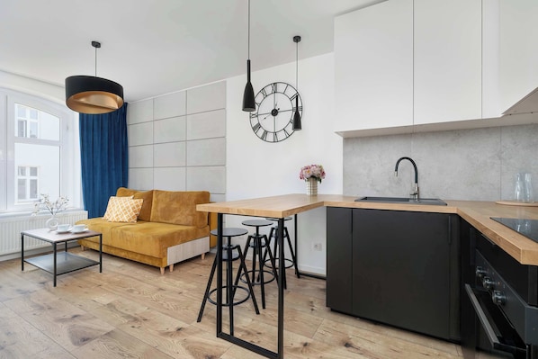 A modern kitchen with a wooden countertop, black cabinets, and a built-in dishwasher.