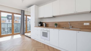 Een moderne keuken met witte kasten, een houten aanrechtblad en een ingebouwde oven.