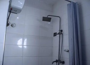 Et badeværelse med hvide flisevægge, en bruseniche og et badeforhæng.