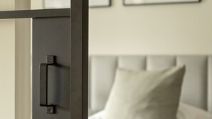 Een slaapkamer met een bed, nachtkastje en een kunstwerk aan de muur.
