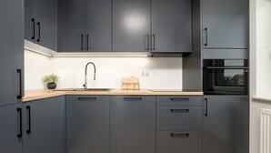 A modern kitchen with grey cabinets, a wooden countertop, a sink, and a built-in oven.
