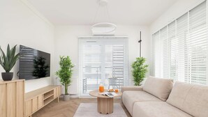 A modern living room with a sofa, a coffee table, a TV, and potted plants.