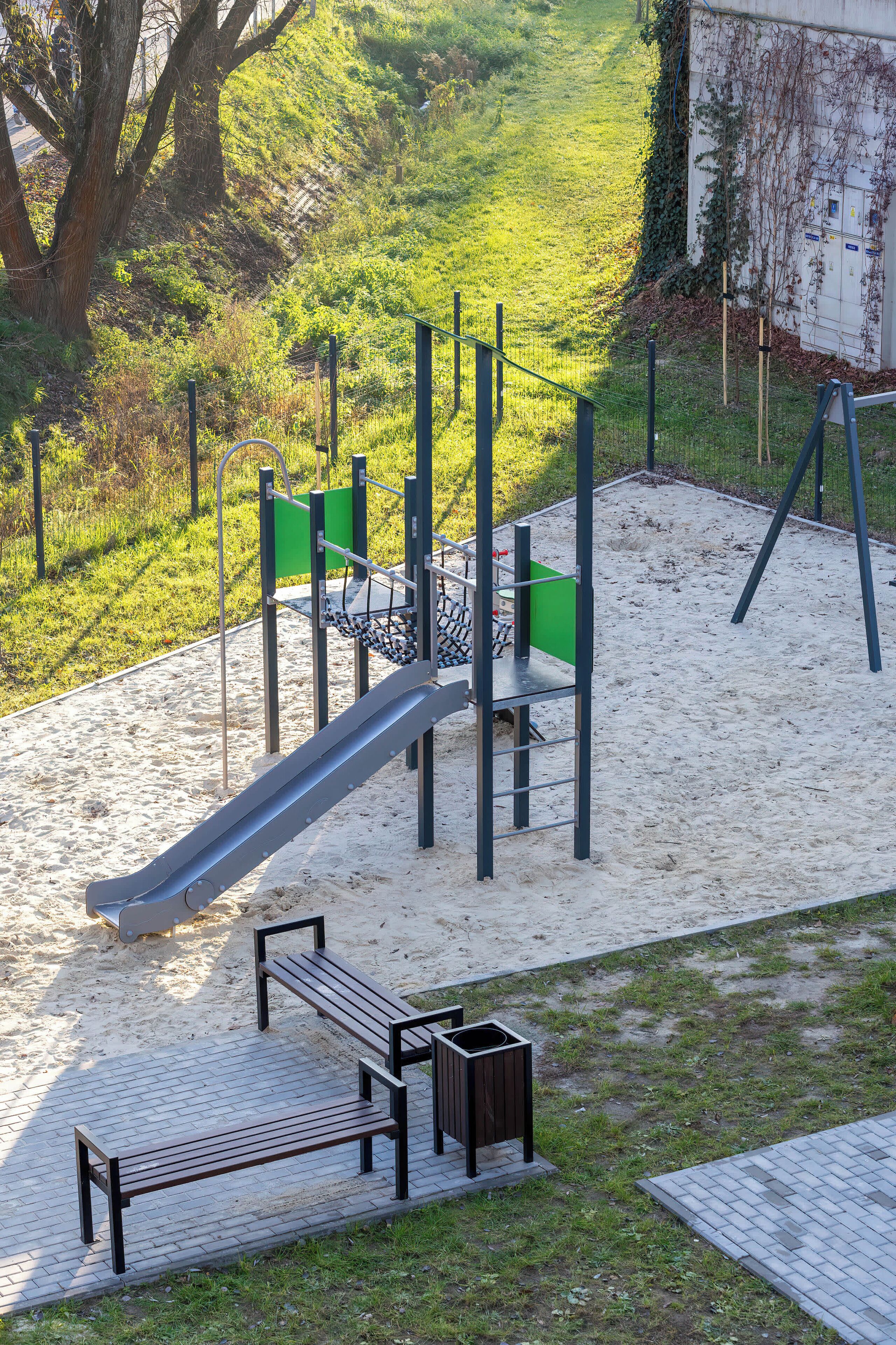 Un parque infantil con tobogán, columpios y un banco.