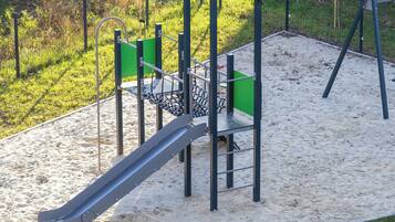 Un parque infantil con tobogán, columpios y un banco.