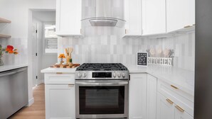 A modern kitchen with white cabinetry, a stainless steel stove, and a tiled backsplash. - Chic Comfort Meets Prime Location Mid-Term Rental in the Heart of Eagle Rock (Los Angeles)