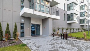 A modern building with a glass entrance, numbered 51F, and a small outdoor seating area with a bench and a trash bin.