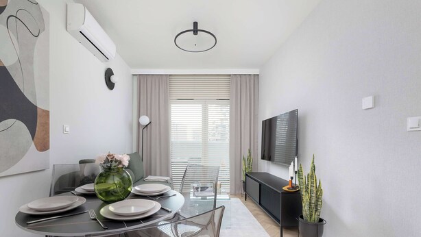 A modern dining area with a glass table, clear chairs, and a vase of flowers.