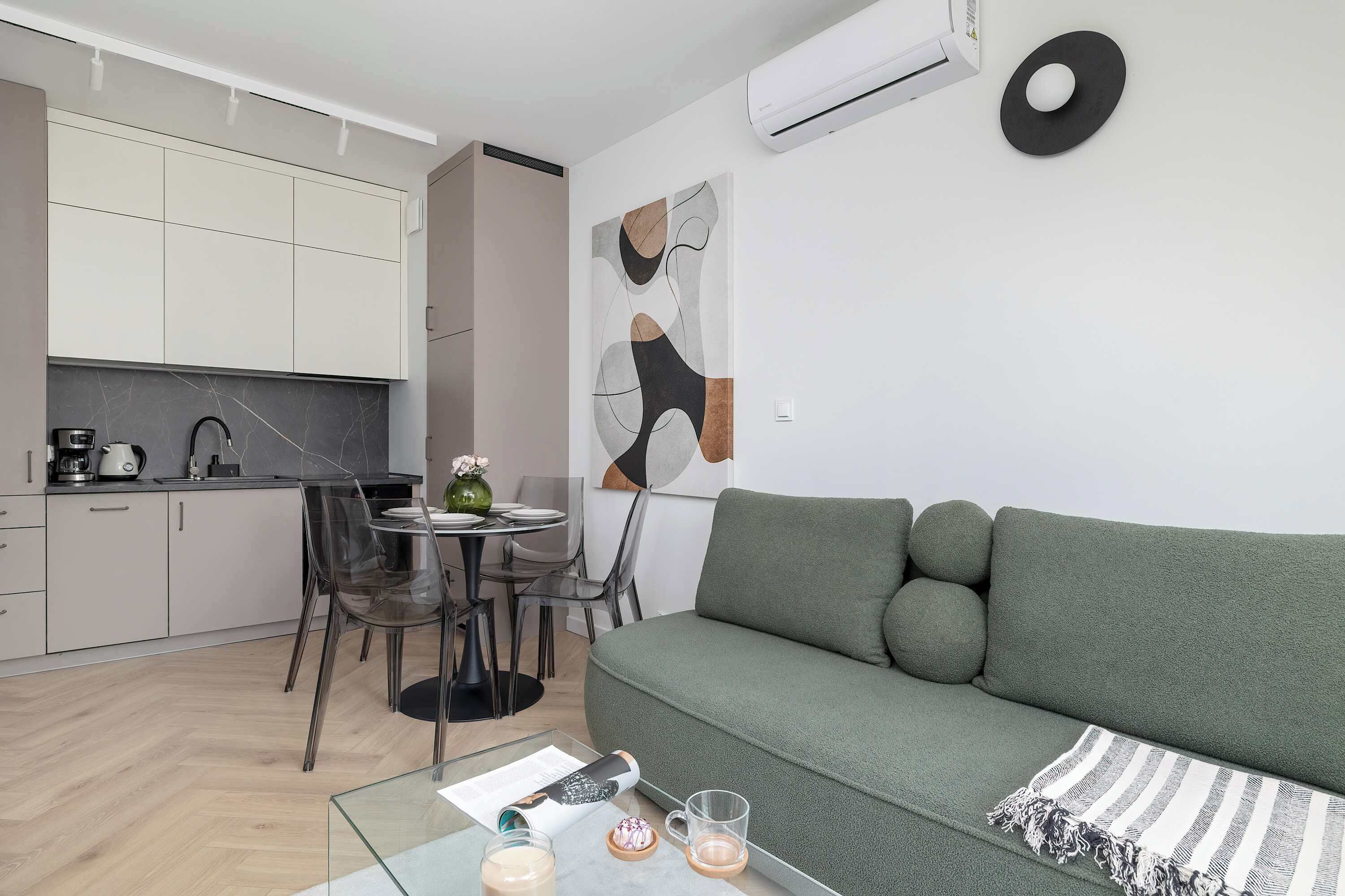 Un espacio habitable moderno con cocina, comedor y un sofá verde.