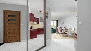 A modern kitchen with red cabinets and a dining area with white chairs and a table.