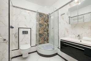 A modern bathroom with a glass-enclosed shower, a toilet, and a vanity with a mirror.