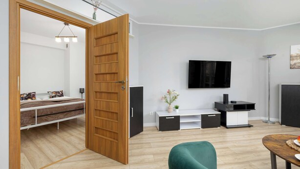 A modern living room with a bed, a TV, and a green armchair.