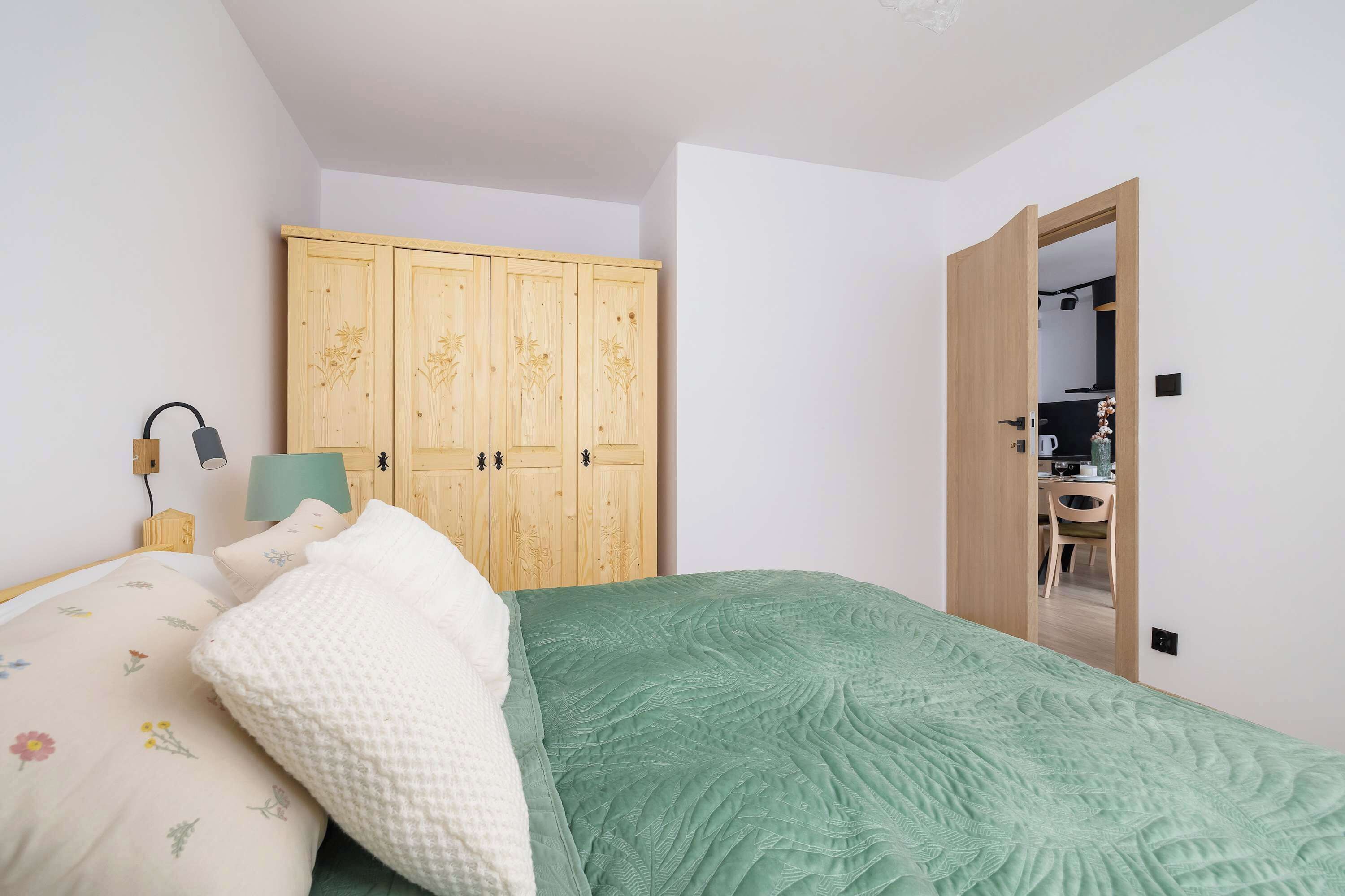 Une chambre à coucher comprenant un lit, une armoire en bois, un bureau et une chaise, le tout situé dans la pièce adjacente.