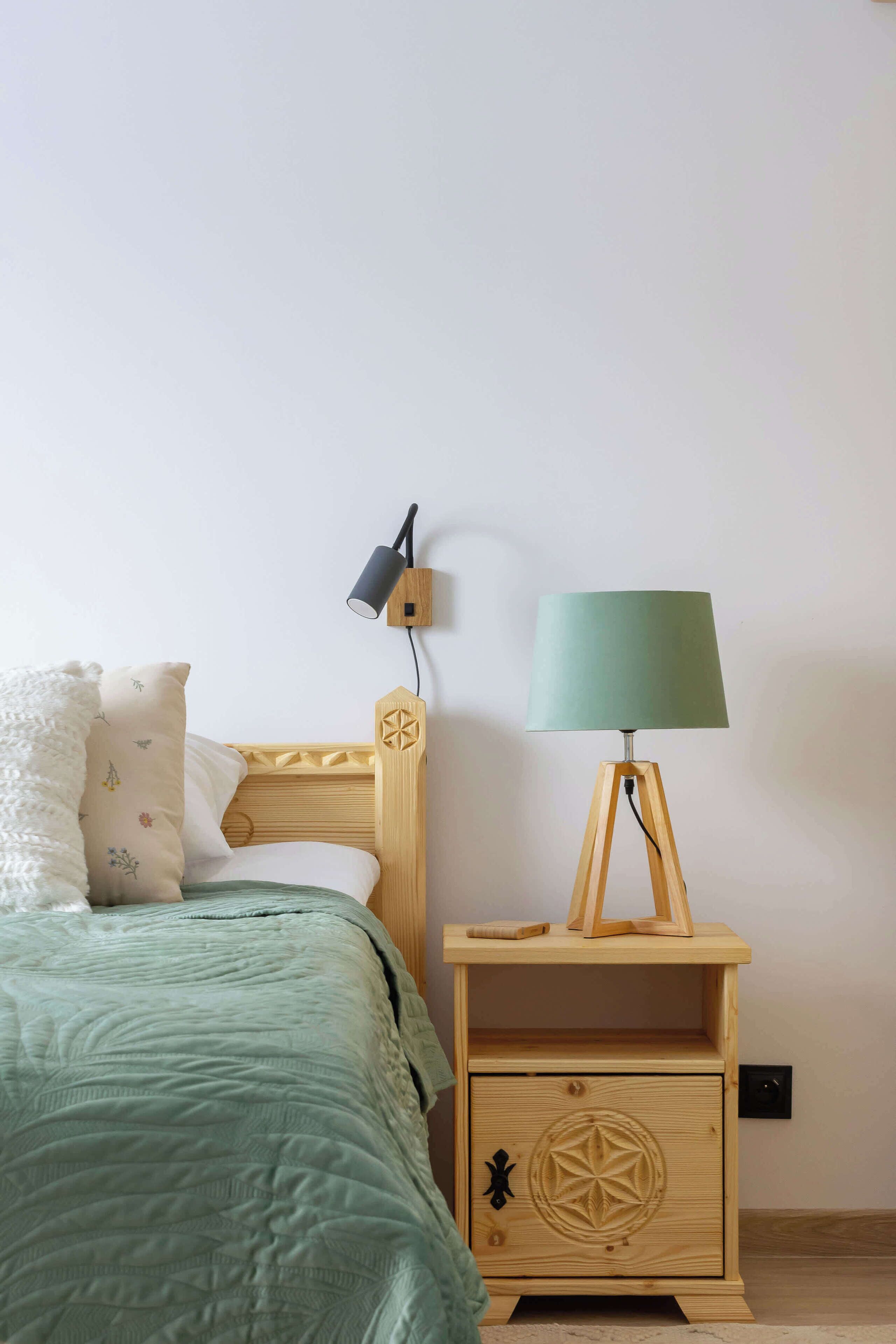 Une chambre à coucher avec un lit, une table de chevet avec une lampe et un luminaire fixé au mur.