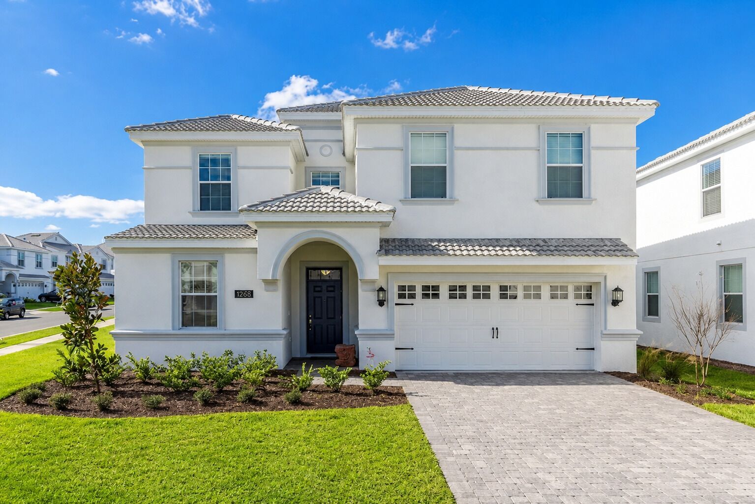A two-story residential building with a front entrance, garage, and a well-maintained lawn.