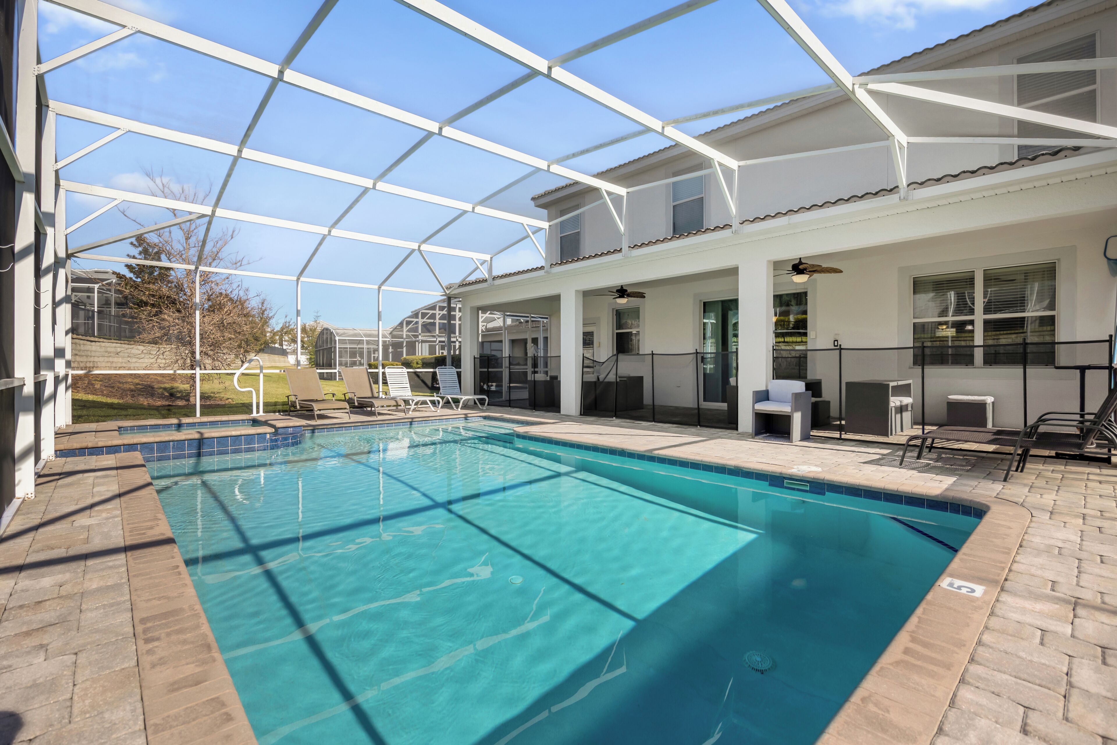 Ein Schwimmbad mit Glasveranda, Liegestühlen und einer Terrassenanlage.
