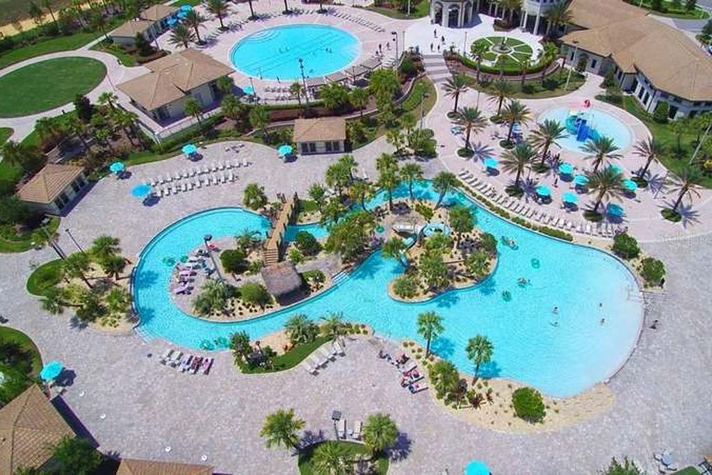 A large swimming pool with multiple lanes, surrounded by palm trees and lounge chairs.