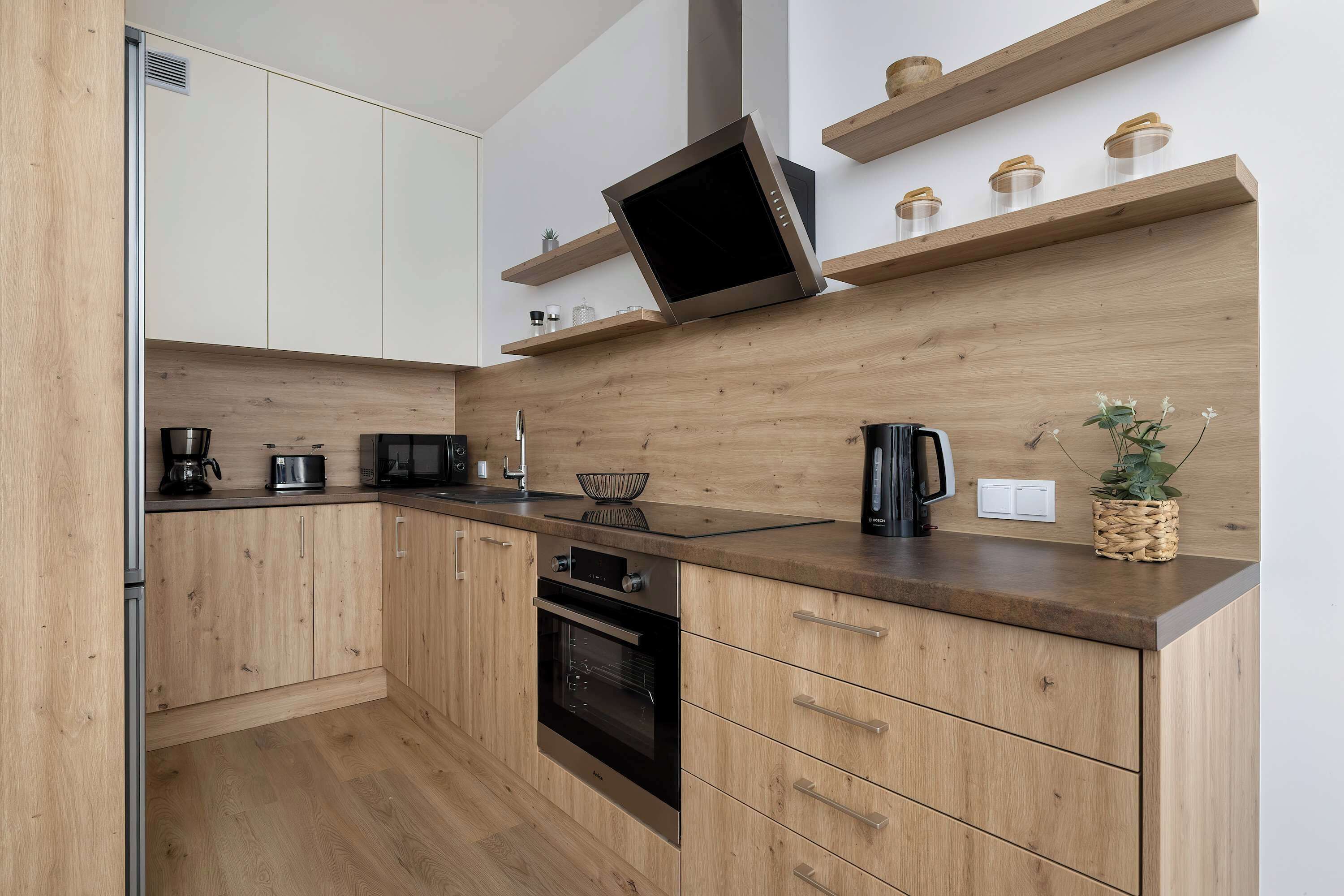 A modern kitchen with wooden cabinets, a built-in oven, and a microwave.
