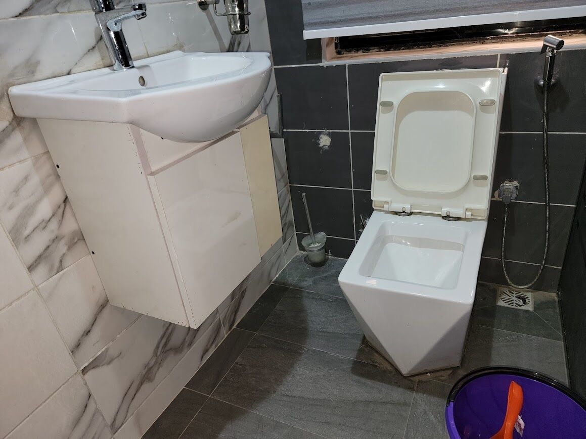 A bathroom with a white sink, a toilet, and a shower area.