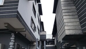 Un edificio moderno y estrecho con fachada geométrica, que cuenta con una escalera central y un muro con diseño.