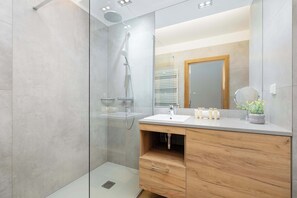 A modern bathroom with a glass-enclosed shower, a wooden vanity with a sink, and a mirror above it.