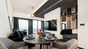 A modern living room with a dining area, large windows, a flat-screen TV, and a view of the city. - Unique Studio with a View | Parking | Jacuzzi (Katowice)