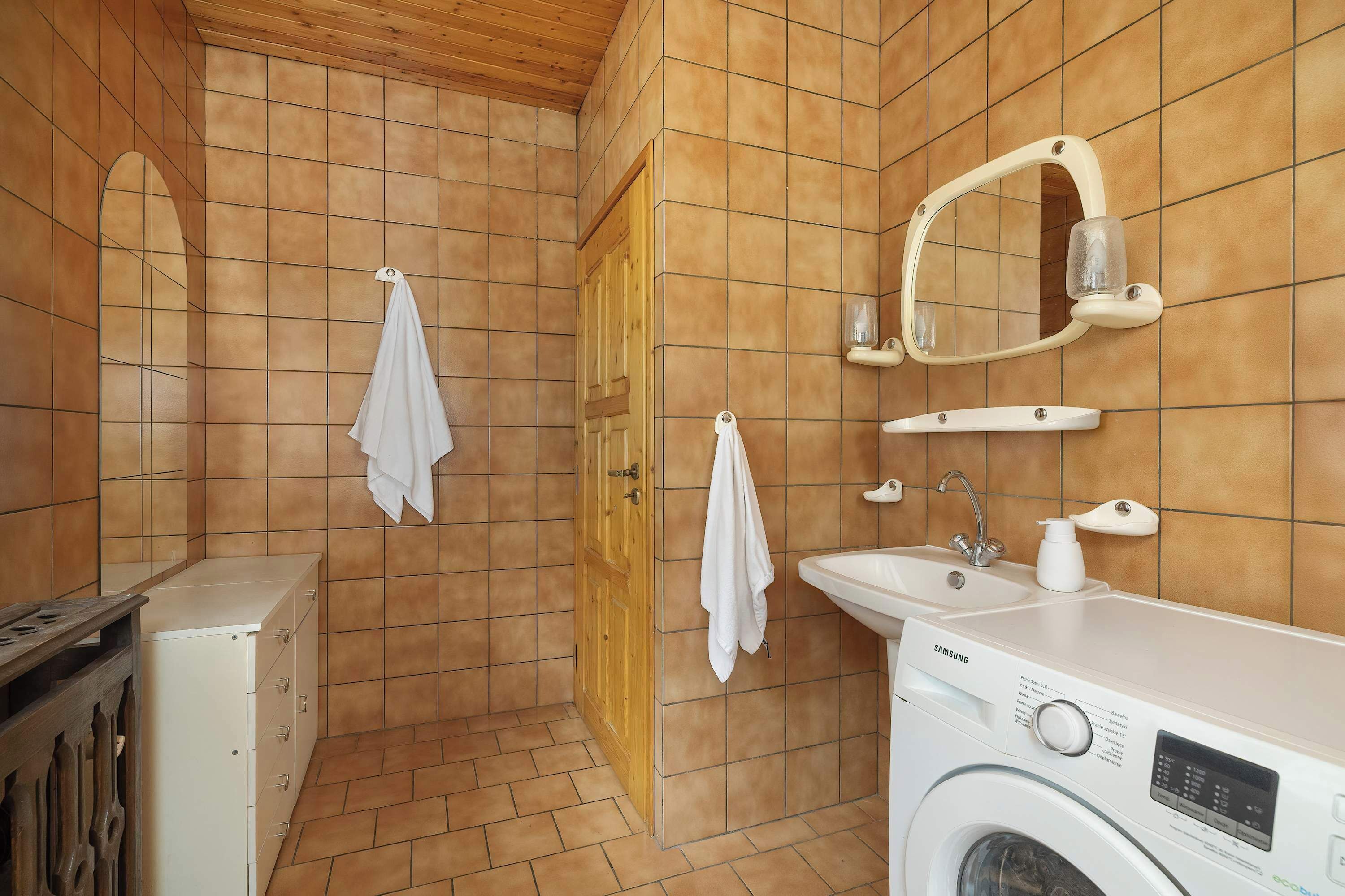 Ein Badezimmer mit Waschmaschine, Waschbecken, Spiegel und Handtuchhalter.