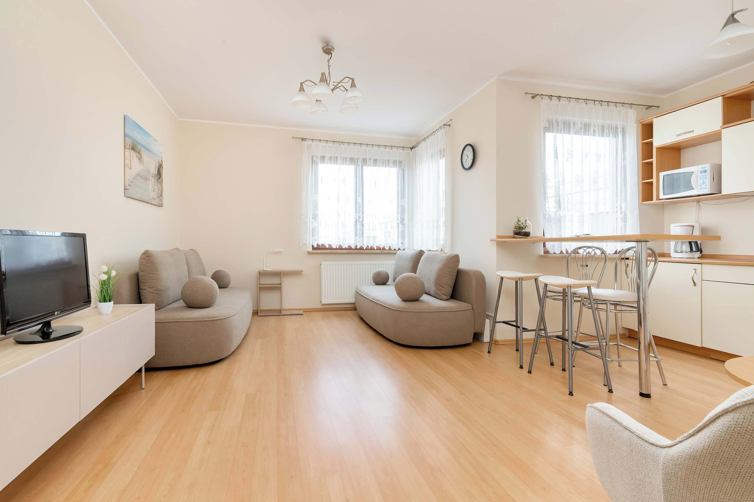 A modern living room with a sofa, TV, and dining area.