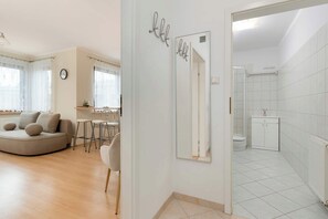 Un salon moderne avec un canapé aux lignes courbes, une table à manger et des chaises. Un grand miroir reflète la pièce.