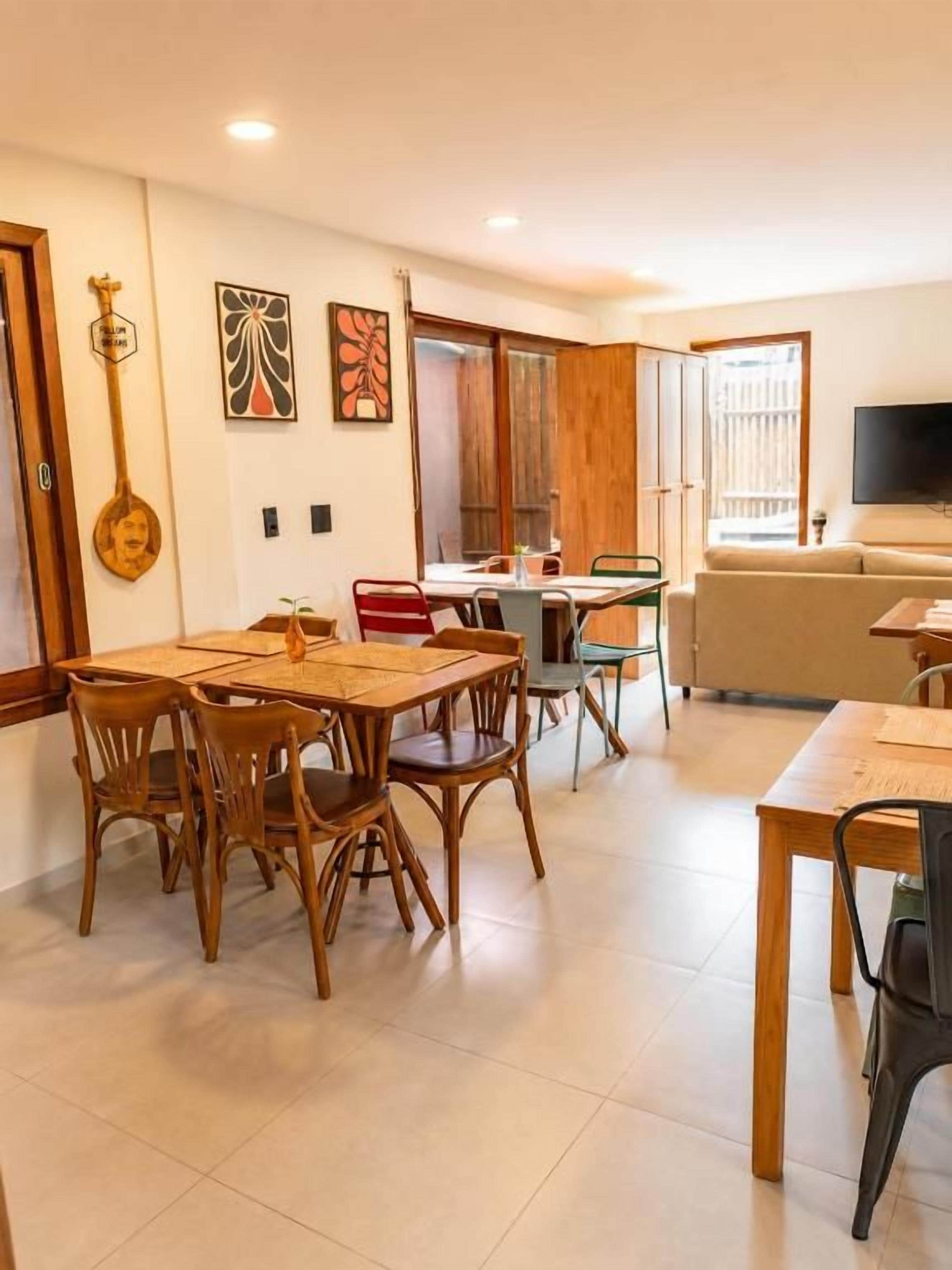A dining area with a wooden table and chairs, a kitchen area with a counter and cabinets, and a living area with a sofa and television.