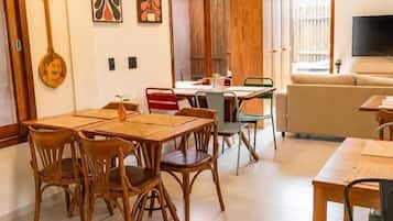 A dining area with a wooden table and chairs, a kitchen area with a counter and cabinets, and a living area with a sofa and television.
