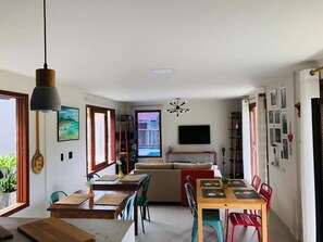 Un espacio habitable moderno con comedor, sofá y televisión montada en la pared.