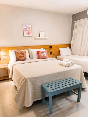 Una habitación de hotel con una cama, un banco y una mesita de noche.