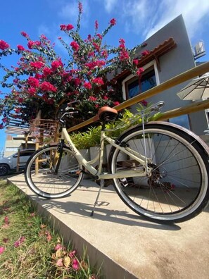 A bicycle parked on a concrete ledge with a building in the background. - Pousada Divino Milagre (Passo de Camaragibe)