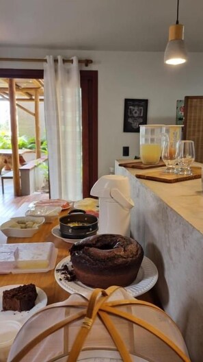 Una cocina con una mesa de madera, un pastel y una cafetera.