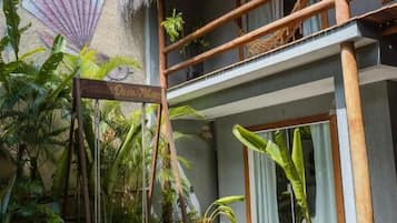 A wooden deck with a swing, a thatched roof balcony, and a mural of a shell.