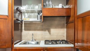 A kitchen with wooden cabinets, a stainless steel sink, a gas stove, and a dish rack. - GuestHost - La Maison Real Palermo (Palermo)