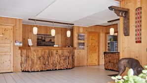 A wooden reception desk with a rustic design, a small statue of a dog, and a wall-mounted sign indicating a personal room. - Heia Gjestegård (Grong)