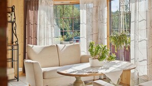 A cozy living room with a beige sofa, a round wooden table, and a potted plant. - Heia Gjestegård (Grong)