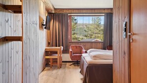 A room with a bed, a chair, a table, and a TV. - Heia Gjestegård (Grong)