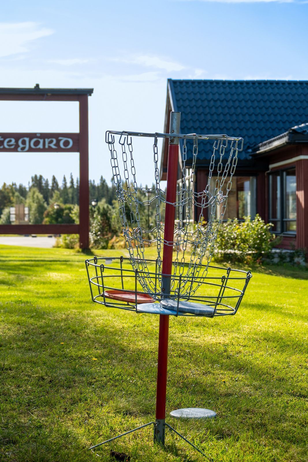 Ein Discgolf-Korb mit Drahtzaun, roter Stange und Metallplatte.