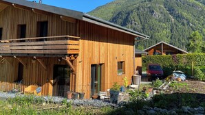A wooden cabin with a balcony, surrounded by a garden and a mountain backdrop. - Hideaway at the foot of Mont Blanc (Les Houches)