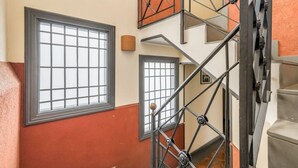 Un interior de varios niveles con escaleras de metal y ventanas amplias.