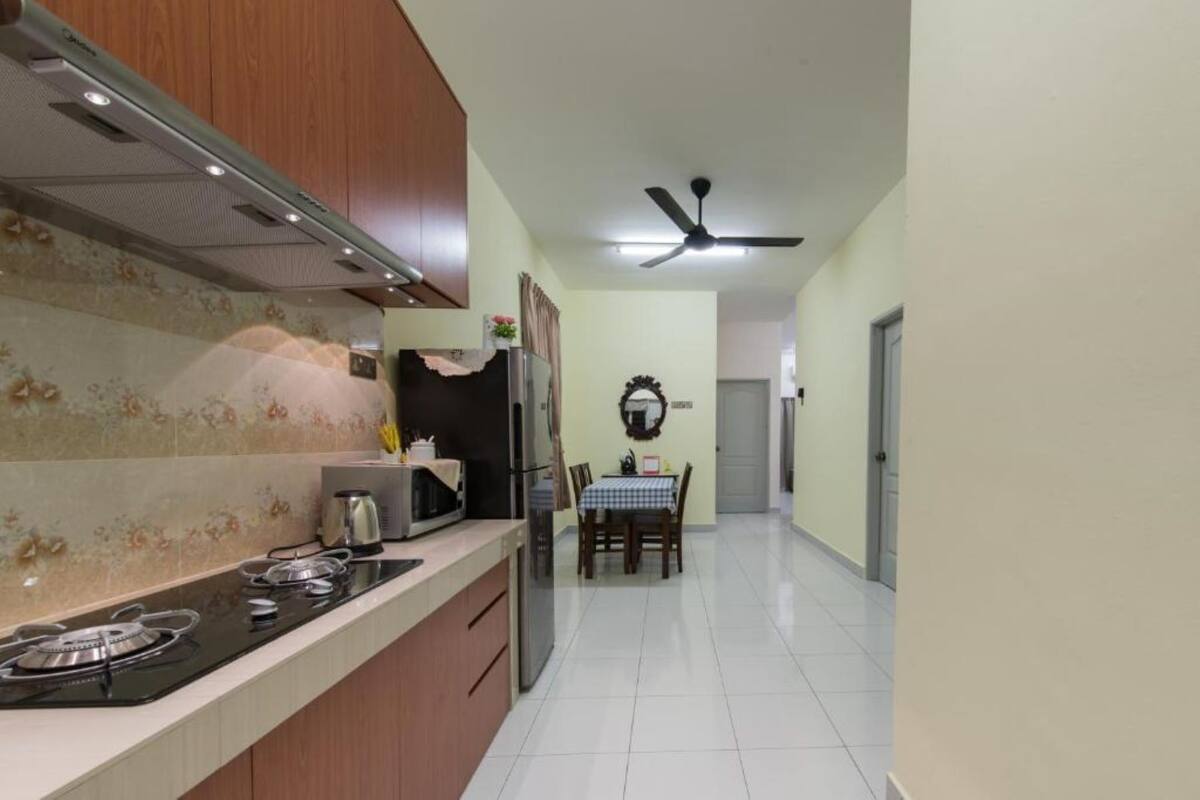 A kitchen with a gas stove, microwave, refrigerator, and a dining area with a table and chairs.