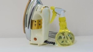 A white ironing board with an iron and a spray bottle on it.