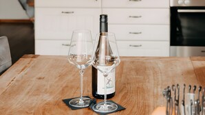 A kitchen with a wooden table, two wine glasses, a wine bottle, and a microwave. - Apartment 'Gorch Fock' with Shared Terrace, Shared Garden and Wi-Fi (Baltrum)
