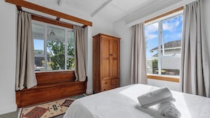 A bedroom with a bed, a wooden wardrobe, and a window with curtains.