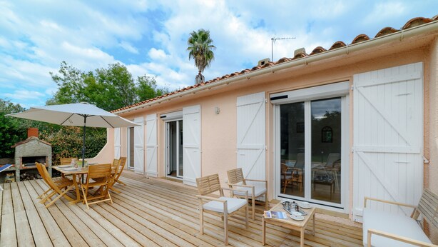 A wooden deck with outdoor furniture, a grill, and a sliding glass door leading to a covered patio. - Holiday Home 'Des Barnèdes' with Private Pool, Wi-Fi and Air Conditioning (Saint-Génis-des-Fontaines)