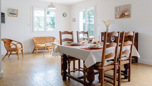 A dining area with a table set for four, surrounded by wooden chairs, a vase with dried plants, and a painting on the wall. - Holiday Home 'Des Barnèdes' with Private Pool, Wi-Fi and Air Conditioning (Saint-Génis-des-Fontaines)