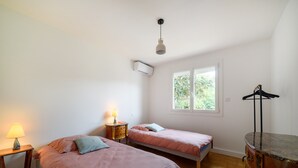 A bedroom with two beds, a window, an air conditioner, a lamp, and a dresser. - Holiday Home 'Des Barnèdes' with Private Pool, Wi-Fi and Air Conditioning (Saint-Génis-des-Fontaines)