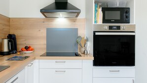 A modern kitchen with a black stove, a microwave, and a stainless steel coffee maker. - Holiday Home 'Des Barnèdes' with Private Pool, Wi-Fi and Air Conditioning (Saint-Génis-des-Fontaines)